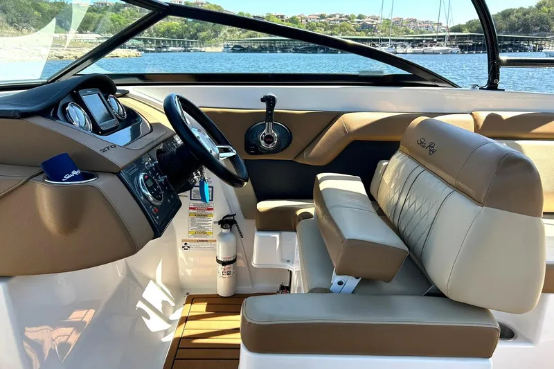 Slide: The Image of 2015 Sea Ray 270 Sundeck interior with tan seating and modern dashboard controls. - 44