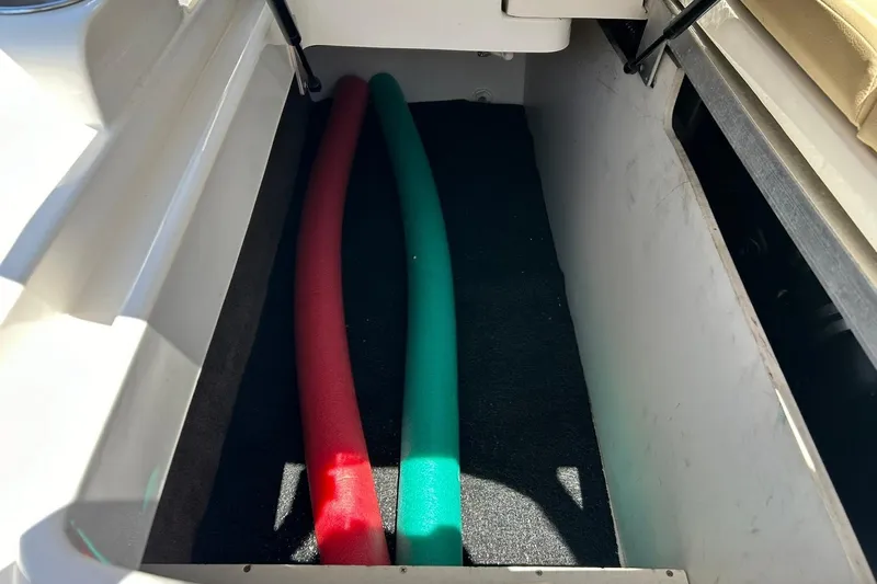 Slide: The Image of Storage compartment on a 2015 Sea Ray 270 Sundeck with red and green pool noodles. - 60