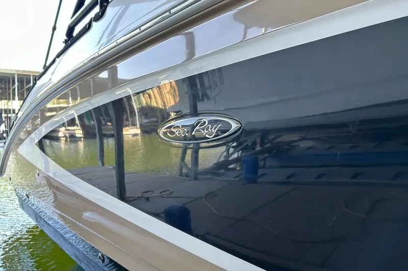 Slide: The Image of 2015 Sea Ray 270 Sundeck boat side view with logo, docked near water. - 65