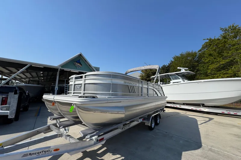 Slide: The Image of 2026 Bennington 22 LFB pontoon boat on trailer, parked outdoors under clear sky. - 3