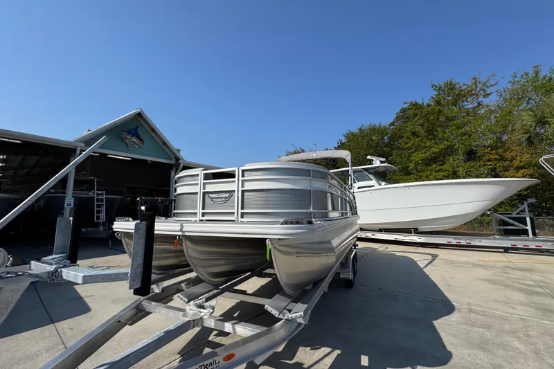 Slide: The Image of 2026 Bennington 22 LFB pontoon boat on trailer, parked outdoors under clear blue sky. - 4