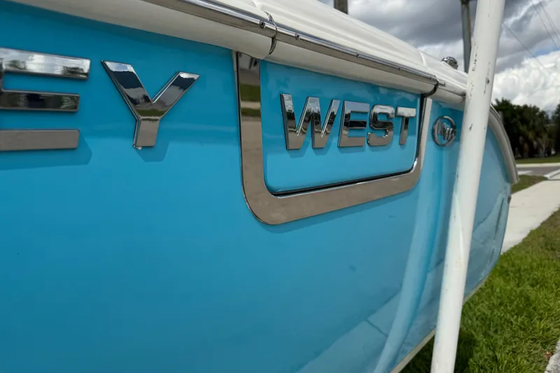 Slide: The Image of 2024 Key West 263 FS boat, close-up of chrome logo on blue hull. - 24