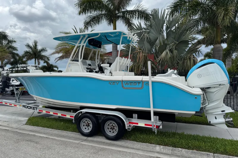 Slide: The Image of 2024 Key West 263 FS boat on trailer, vibrant blue, parked near palm trees. - 3