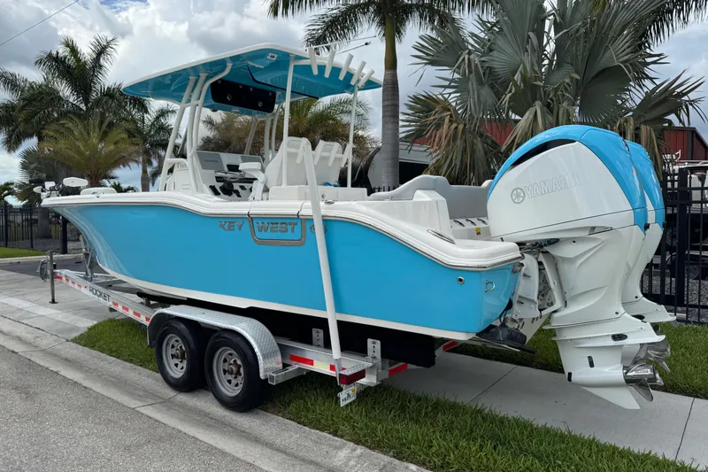 Slide: The Image of 2024 Key West 263 FS boat on trailer with Yamaha engine, parked near palm trees. - 4