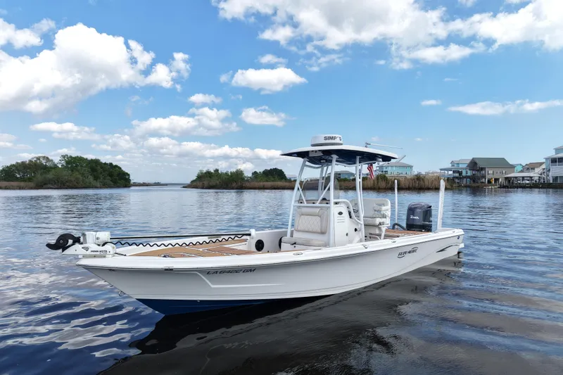 Slide: The Image of 2021 Blue Wave 2600 PureBay boat on calm water under a clear sky. - 11
