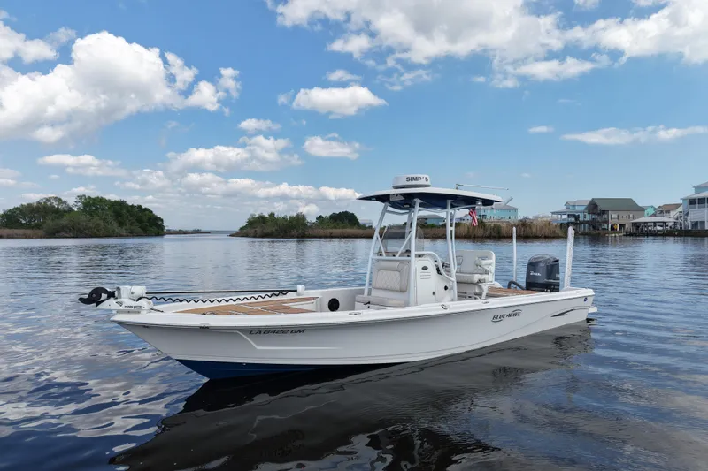 Slide: The Image of 2021 Blue Wave 2600 PureBay boat on calm water under a clear blue sky. - 12