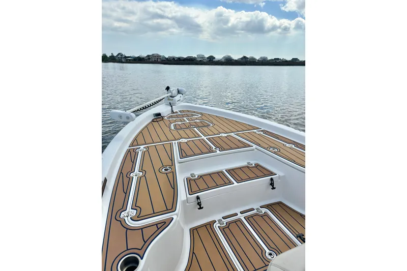 Slide: The Image of 2021 Blue Wave 2600 PureBay boat deck with wood finish on calm water. - 15