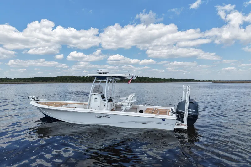 Slide: The Image of 2021 Blue Wave 2600 PureBay boat on calm water under a blue sky with clouds. - 2