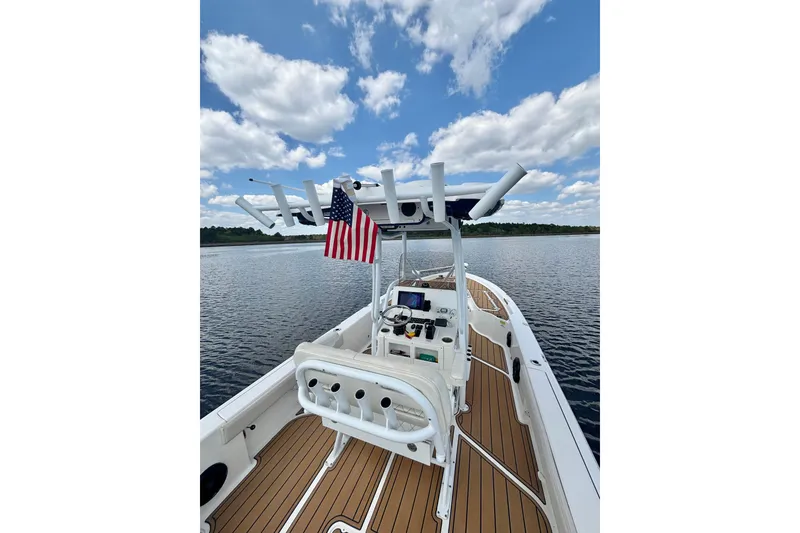 Slide: The Image of 2021 Blue Wave 2600 PureBay boat on calm water, featuring a sleek deck and American flag. - 22