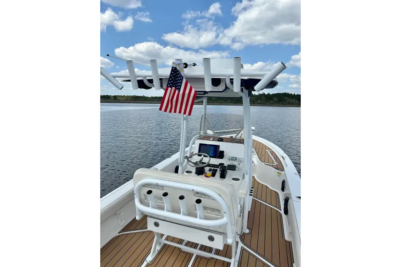 Slide: The Image of 2021 Blue Wave 2600 PureBay boat on calm water, featuring a sleek console and American flag. - 23