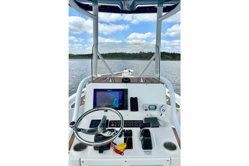 Slide: The Image of 2021 Blue Wave 2600 PureBay boat dashboard with navigation equipment on a calm lake. - 26