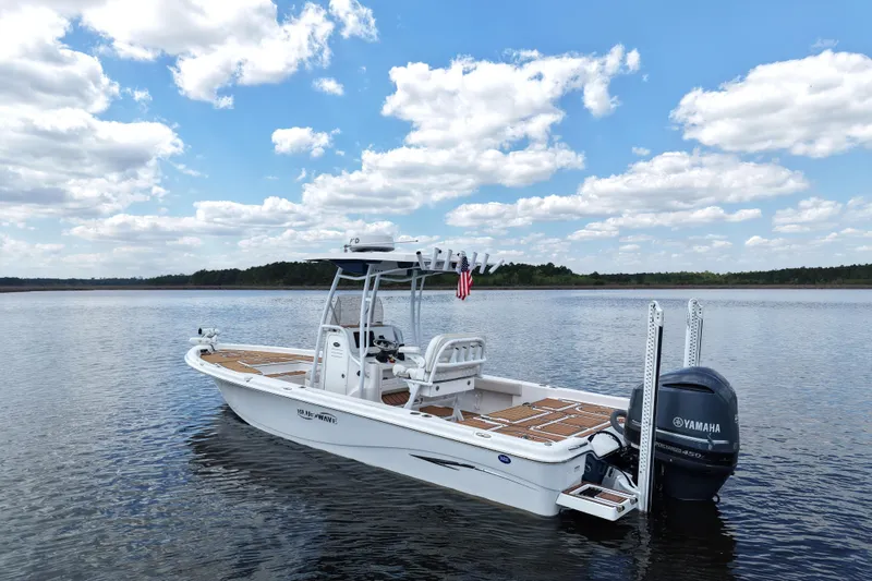 Slide: The Image of 2021 Blue Wave 2600 PureBay boat on calm water under a partly cloudy sky. - 8