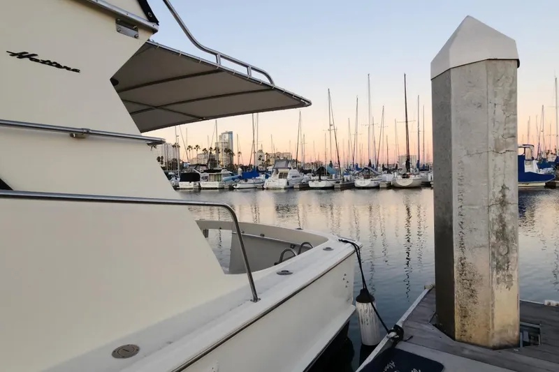 Slide: The Image of 1978 Hatteras 45 Express Sportfish docked at marina during sunset, surrounded by sailboats. - 16