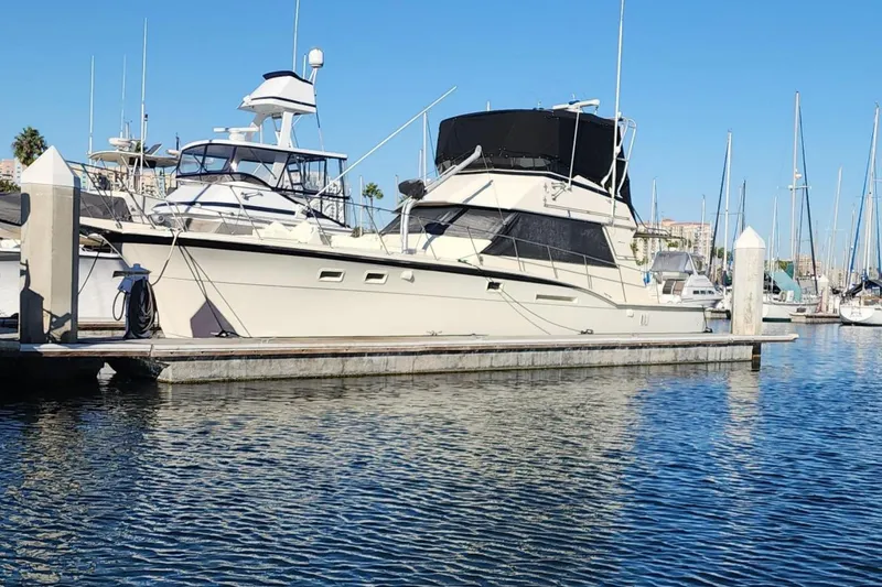 Slide: The Image of 1978 Hatteras 45 Express Sportfish yacht docked at marina under clear blue sky. - 4