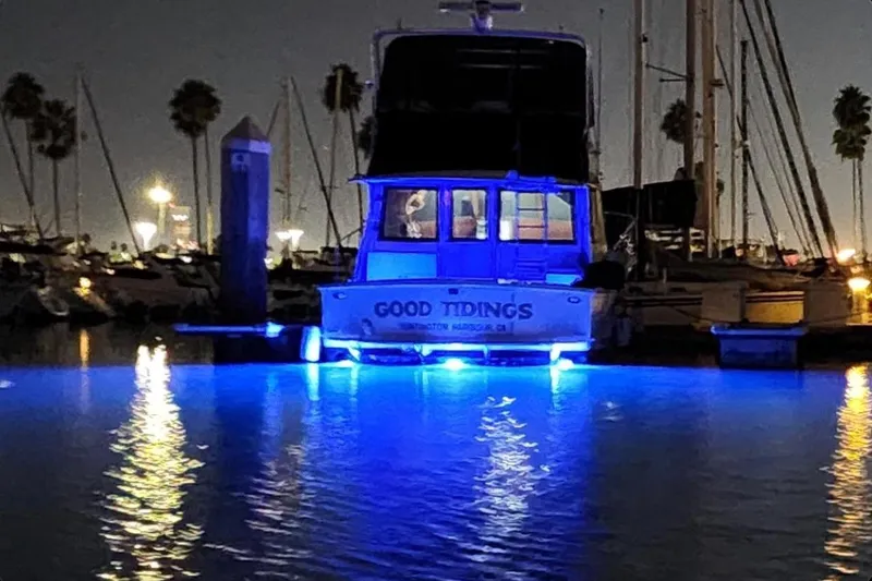 Slide: The Image of 1978 Hatteras 45 Express Sportfish boat illuminated with blue lights at night in a marina. - 9