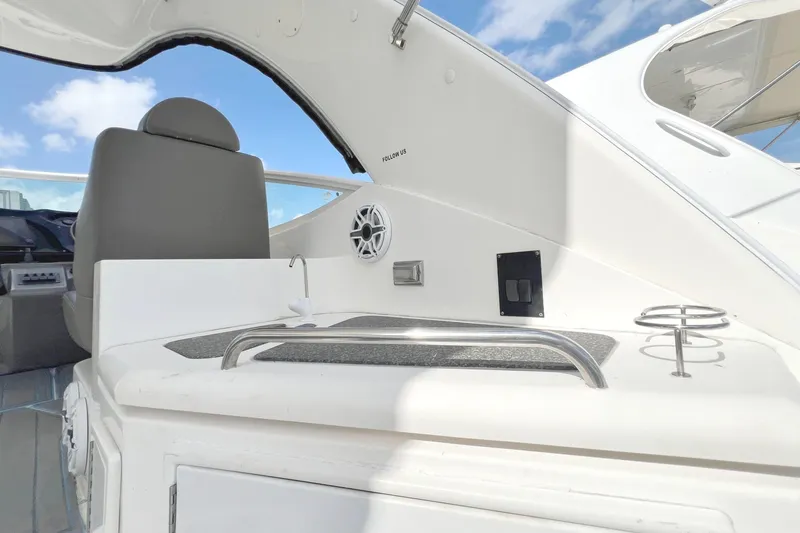 Slide: The Image of 2005 Cruisers Yachts 440 Express cockpit with seating and amenities under blue sky. - 18