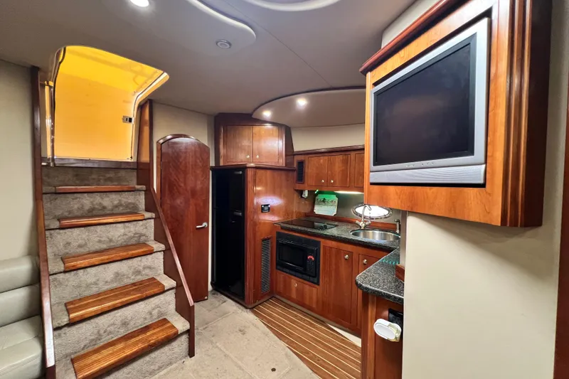 Slide: The Image of Interior of 2005 Cruisers Yachts 440 Express, featuring kitchen and stairs with wood accents. - 57