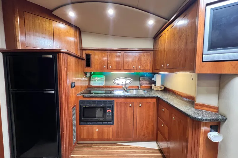 Slide: The Image of Luxurious 2005 Cruisers Yachts 440 Express kitchen with wood cabinetry and modern appliances. - 58
