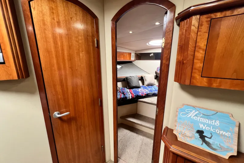 Slide: The Image of 2005 Cruisers Yachts 440 Express cabin interior with wooden doors and cozy bedding. - 76