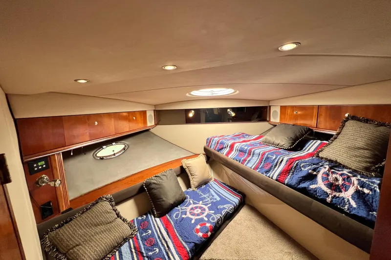 Slide: The Image of Interior cabin of 2005 Cruisers Yachts 440 Express with nautical-themed bedding and wood accents. - 77