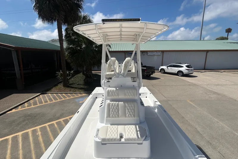 Slide: The Image of 2026 Shallow Sport 25 X3 boat with T-top and cushioned seating, parked outdoors. - 28