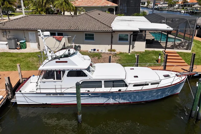 The Image of Huckins Atlantic 44 yacht, 2006 model, docked by a waterfront home with a pool. - 1