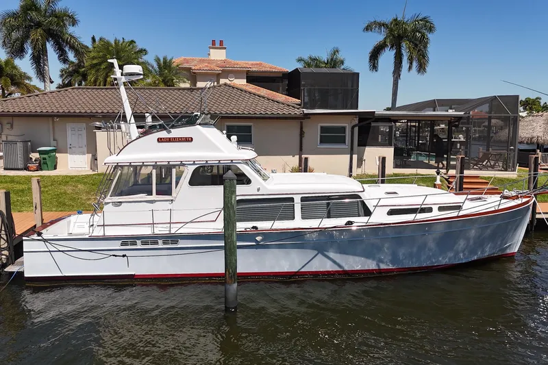 Slide: The Image of 2006 Huckins Atlantic 44 yacht docked by a waterfront home with palm trees. - 13