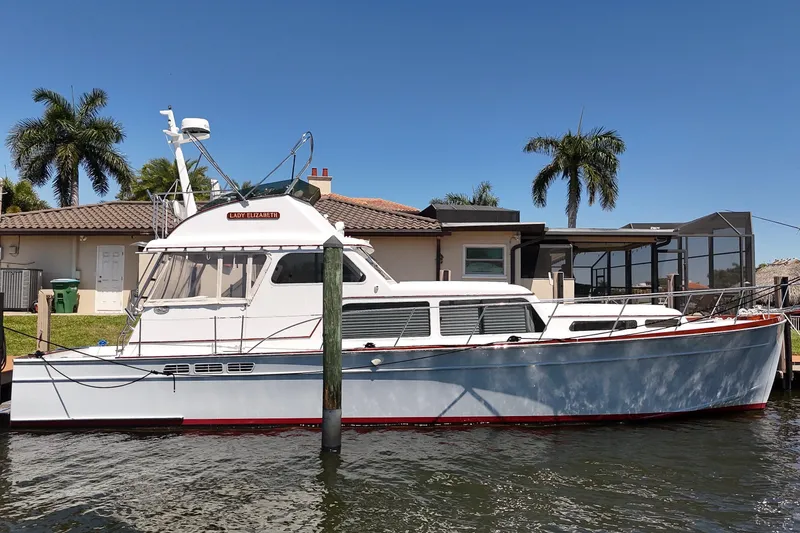 Slide: The Image of 2006 Huckins Atlantic 44 yacht docked by a waterfront home with palm trees. - 6