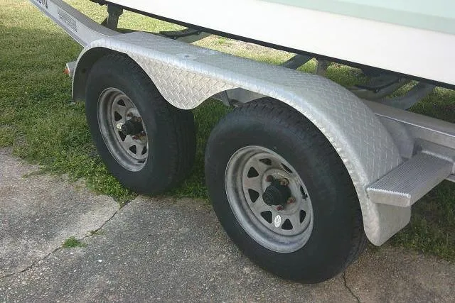 Slide: The Image of Trailer wheels for 2016 Robalo R200 Center Console boat on grass and pavement. - 15