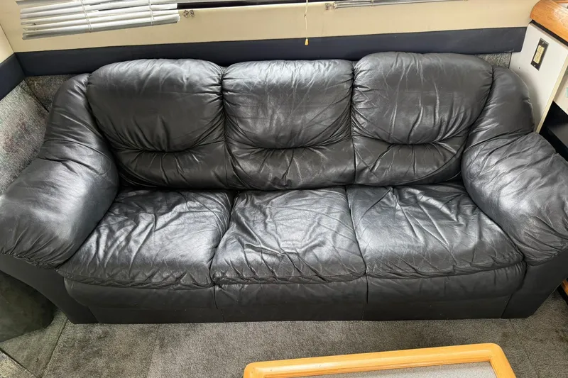 Slide: The Image of Black leather sofa inside 1991 Bayliner 4387 Motoryacht, with carpeted flooring and window blinds. - 32
