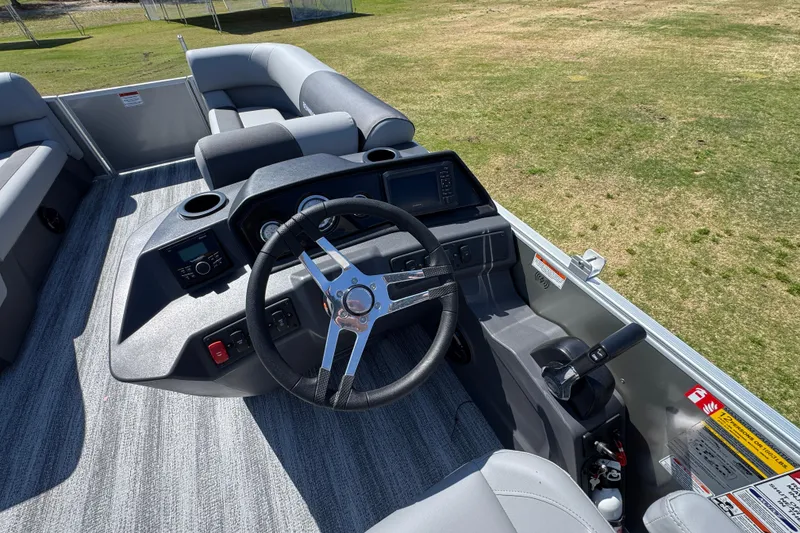 Slide: The Image of 2026 Bennington 22 S Fish boat interior with steering wheel and seating on grassy background. - 19