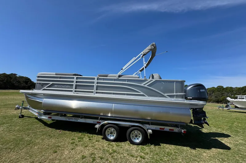 Slide: The Image of 2026 Bennington 22 S Fish pontoon boat on trailer, parked on grassy field. - 9