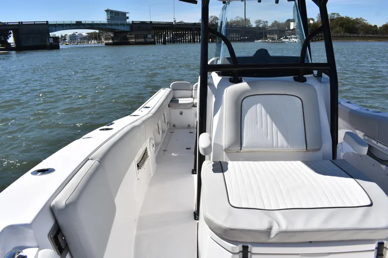 Slide: The Image of 2021 Sea Fox 268 Commander boat interior with white seating, near a bridge on the water. - 25