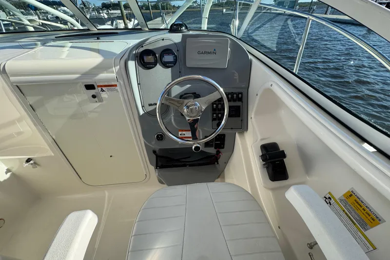 Slide: The Image of 2014 Wellcraft 252 Coastal boat cockpit with steering wheel and Garmin navigation system. - 11