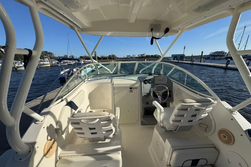 Slide: The Image of 2014 Wellcraft 252 Coastal boat interior at marina, featuring helm and seating. - 13