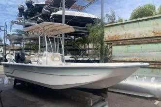 Slide: The Image of 2016 Sundance B22CCR boat in storage, surrounded by other vessels and palm trees. - 1