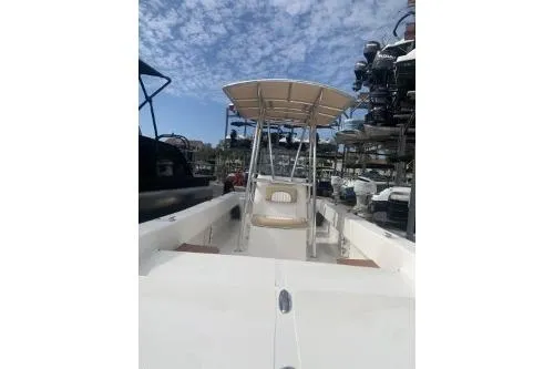 Slide: The Image of 2016 Sundance B22CCR boat with T-top, docked under a partly cloudy sky. - 2