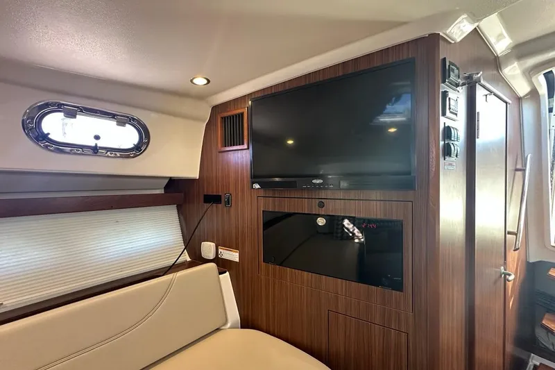 Slide: The Image of 2020 Pursuit OS 355 Offshore cabin interior with TV and wood paneling. - 20