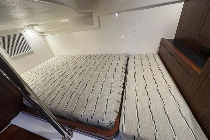 Slide: The Image of 2020 Pursuit OS 355 Offshore cabin interior with twin beds and wooden cabinetry. - 26