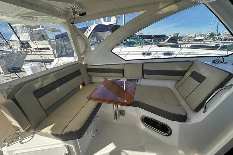 Slide: The Image of 2020 Pursuit OS 355 Offshore boat interior with cushioned seating and wooden table. - 6