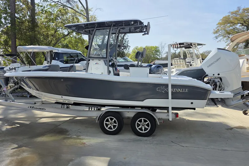 Slide: The Image of 2021 Crevalle 24 HCO boat on trailer, parked outdoors with trees in background. - 14