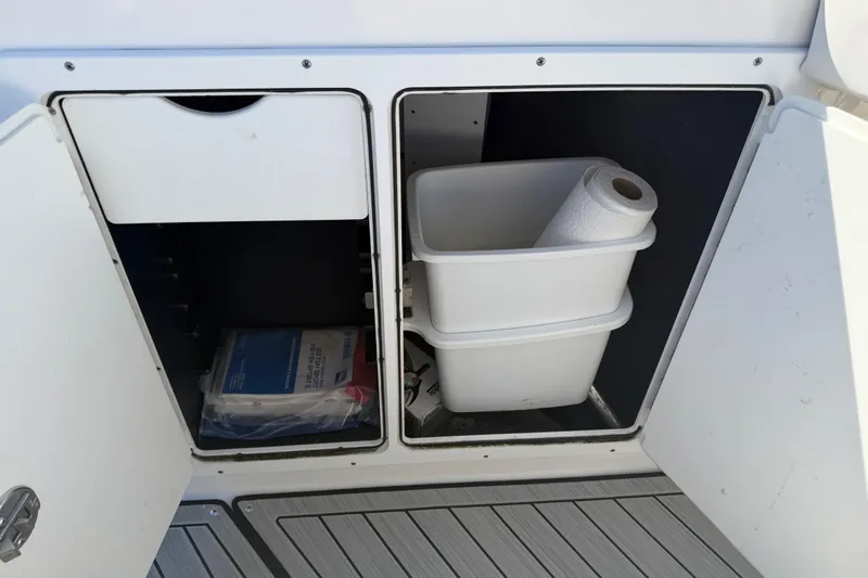 Slide: The Image of Storage compartments on a 2022 Yamaha Boats 252 FSH Sport, featuring paper towels and manuals. - 14