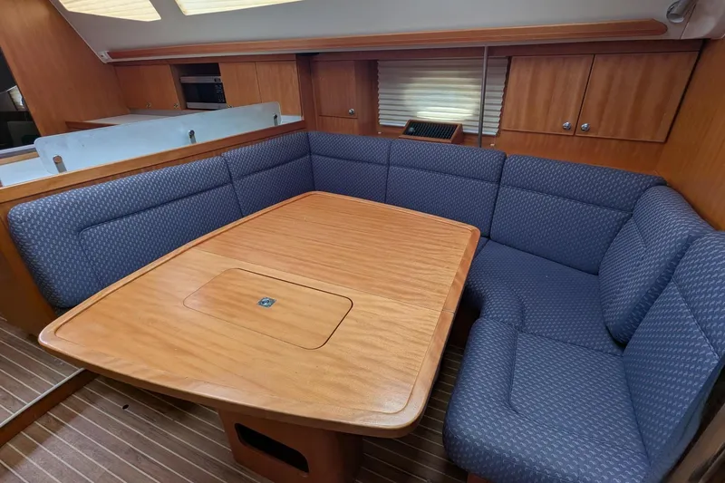 Slide: The Image of Cozy dining area in 2007 Elan Impression 434 yacht with wooden table and blue cushioned seating. - 17