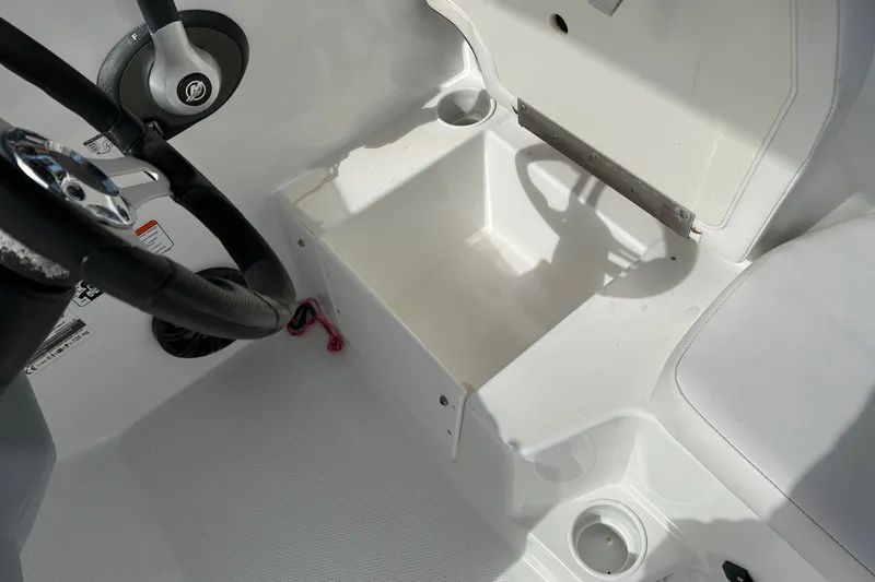 Slide: The Image of 2021 Tahoe T16 boat interior with open storage compartment and steering wheel. - 16