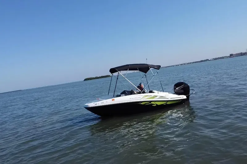 Slide: The Image of 2021 Tahoe T16 boat cruising on a calm lake under a clear blue sky. - 19