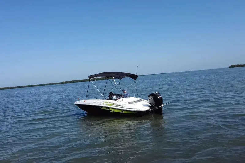 Slide: The Image of 2021 Tahoe T16 boat with canopy on calm water under clear blue sky. - 20