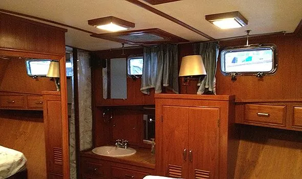 Slide: The Image of 1986 Sea Ranger 47 Pilothouse interior with wood paneling, sink, and porthole windows. - 12