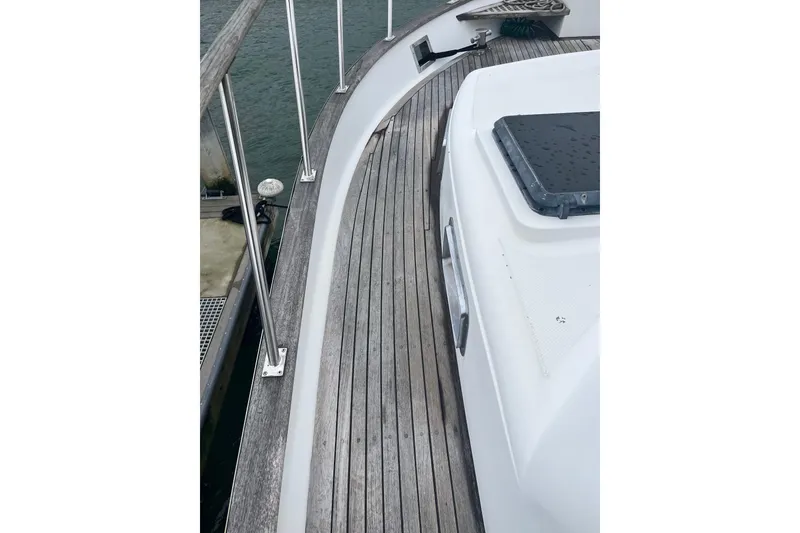 Slide: The Image of 1986 Sea Ranger 47 Pilothouse deck with wooden flooring and railing, docked by the water. - 21