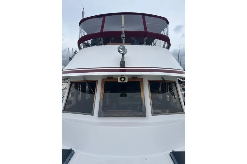 Slide: The Image of 1986 Sea Ranger 47 Pilothouse boat with maroon accents, docked at a marina. - 27