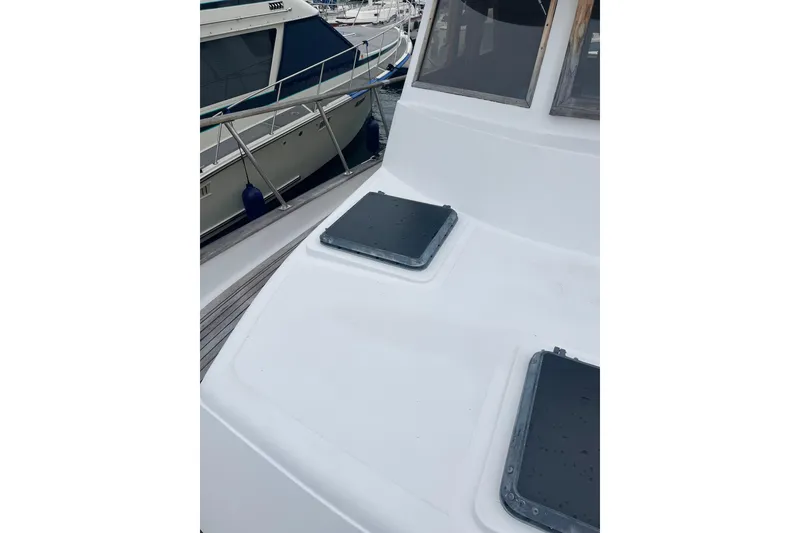 Slide: The Image of 1986 Sea Ranger 47 Pilothouse deck with hatches, docked beside another boat. - 28